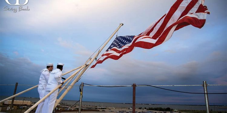 Navy sailors hoist the flag