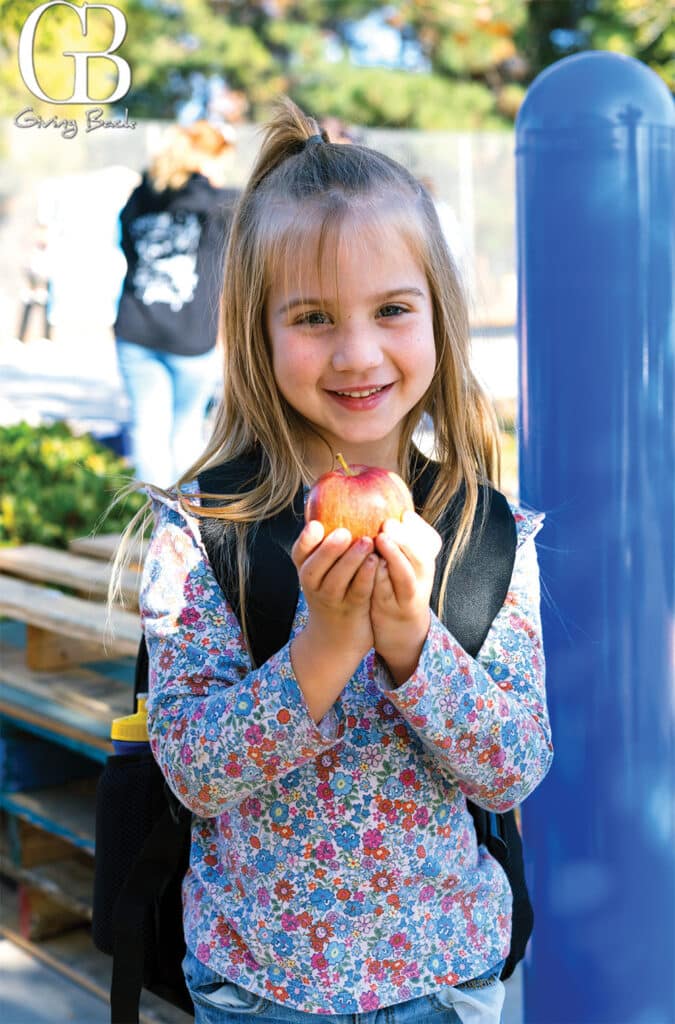 A child receives an apple at a school pantry held at Hancock Elementary in Tierrasanta a school with a high population of military families