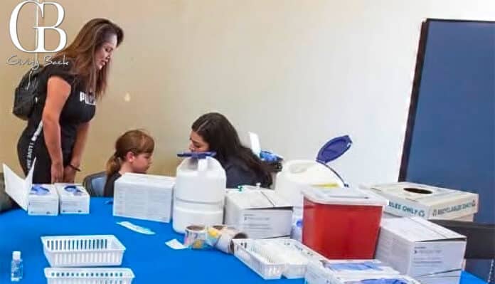 Volunteer helps a young girl at a table filled with medical supplies during a Giving Back event.