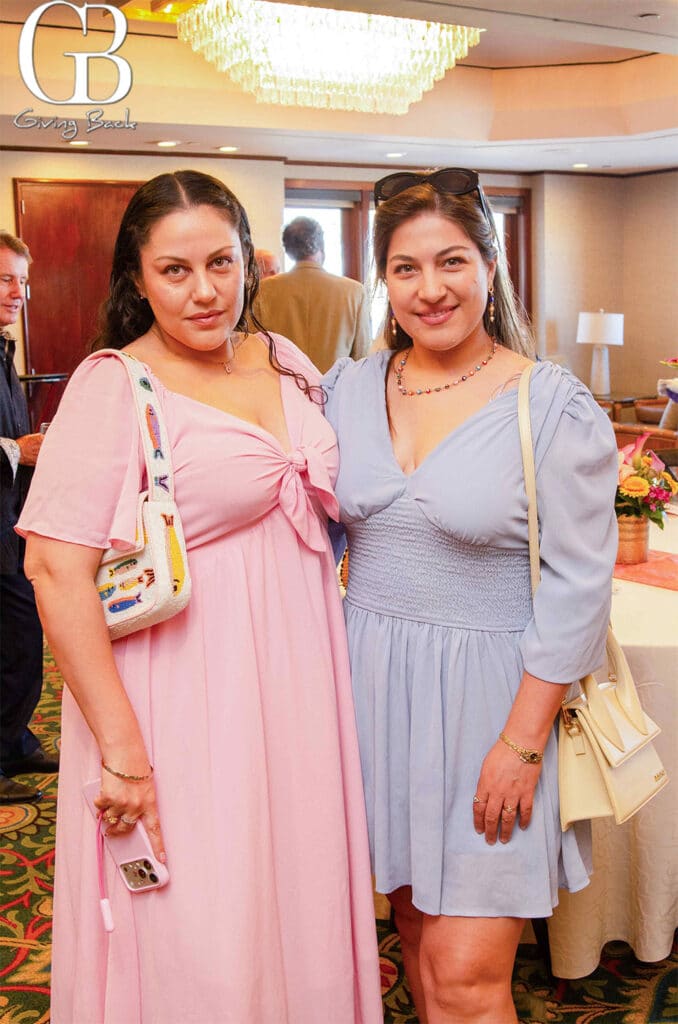 Aurora and Teresa Magdaleno'Giving Back' logo in the background. 🡒 Informative photo context for a fundraiser or gathering.