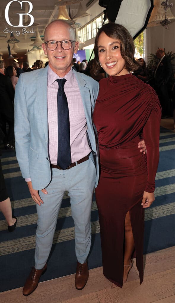 James-Arp-and-Aura-Barragan - GB Magazine James Arp and Aura Barragan'Giving Back' logo in the background.